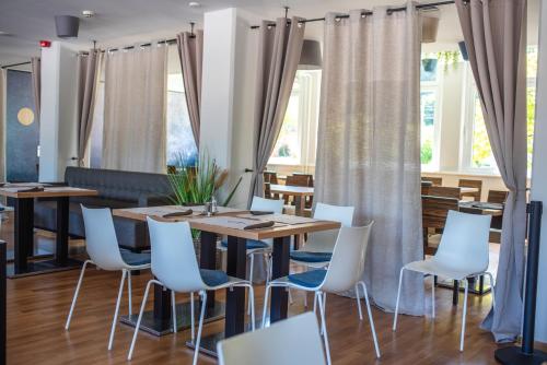 a dining room with tables and white chairs at Hotel Špica Laško in Laško