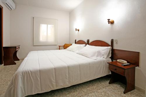 a bedroom with a large white bed and a wooden table at Hotel Canadá in Tarragona