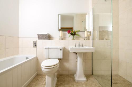 a bathroom with a toilet and a sink and a bath tub at Barrow Hill Barns in Petersfield