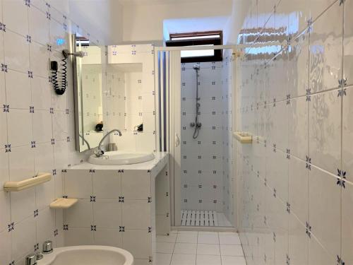 ein weißes Badezimmer mit einem Waschbecken und einem Spiegel in der Unterkunft Casa Papuzza in Malfa
