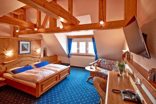 a bedroom with a bed and a couch and a tv at Hotel und Restaurant Bommersheim in Eschborn