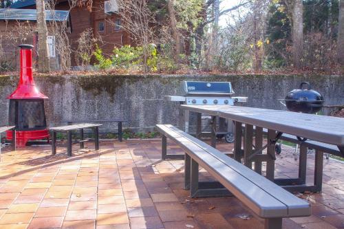 a picnic table and benches with a grill and a barbecue at Maple Chalet Hakuba in Hakuba