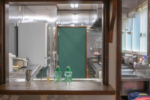 a kitchen with a sink and two green bottles on a counter at Maple Chalet Hakuba in Hakuba