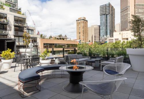 un patio en la azotea con mesas, sillas y una hoguera en Lancemore Crossley St. Melbourne en Melbourne