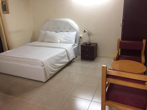 a bedroom with a white bed and a wooden table at Noor Majan Camp in Bilād Manaḩ