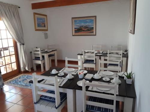 a dining room with a black table and chairs at Baleia Guest Lodge in Hermanus