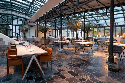 a restaurant with tables and chairs and windows at Fletcher Hotel Château De Raay in Baarlo