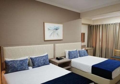 een hotelkamer met 2 bedden met blauwe kussens bij Regal Inn North Beach in Durban