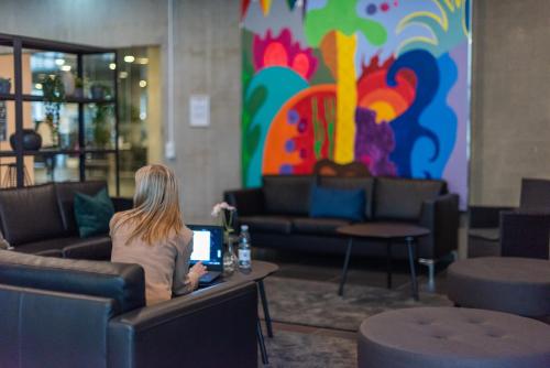 a woman sitting at a table in a lobby with a laptop at Cabinn Apartments in Copenhagen