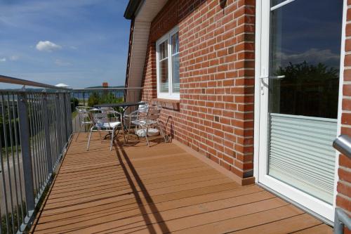 a wooden deck with chairs and a table on it at Haus am Deich Feriendomizil mit Balkon in Baabe
