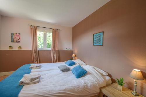 a bedroom with a large white bed with blue pillows at Domaine d'Essendiéras in Saint-Médard-dʼExcideuil