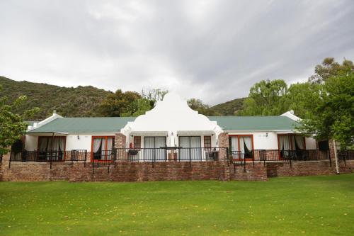 a house with a green roof on a grass field at De Oude Meul Country Lodge & Restaurant in Oudtshoorn