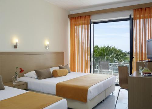 a hotel room with two beds and a balcony at Atlantica Thalassa Hotel in Kos Town