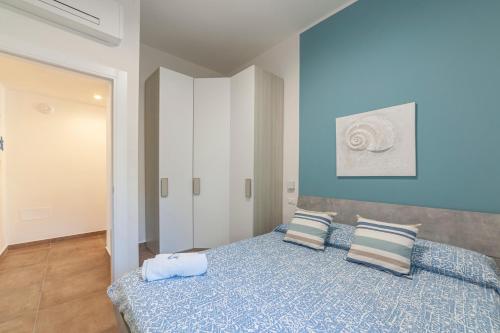 a blue bedroom with a bed with two pillows at Prima dell'Elba Family Apartments in Piombino