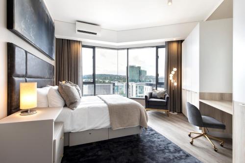 a hotel room with a bed and a desk and a window at Black Marble - Menlyn Residence Apartments in Pretoria