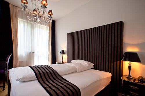 a bedroom with a large bed and a chandelier at Hotel Aleksandra in Düsseldorf