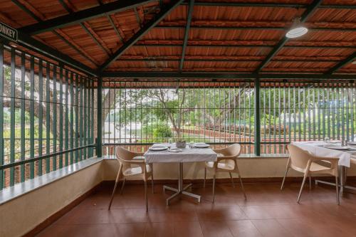 a table and chairs in a room with windows at KSTDC Hotel Mayura Sangama Mekedatu in Mulhalli