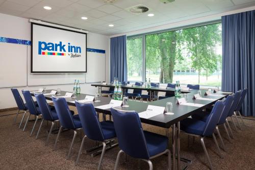 a conference room with long tables and blue chairs at Park Inn by Radisson Frankfurt Airport in Frankfurt/Main