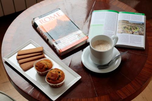 ein Tisch mit einem Buch und einer Tasse Kaffee und Muffins in der Unterkunft Residenza Delle Arti in Rom