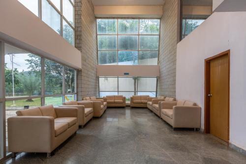 a waiting room with leather chairs and large windows at KSTDC Hotel Mayura Sangama Mekedatu in Mulhalli