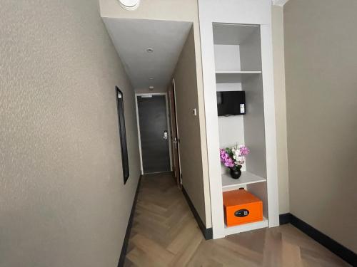 a hallway leading to a room with a door and flowers at H3 Hotel Rotterdam City Center in Rotterdam