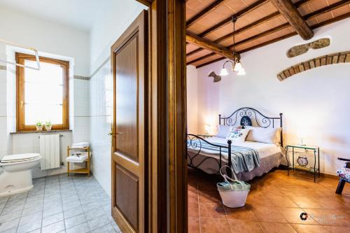 Un dormitorio con una cama y un baño con inodoro. en Bio Fattoria Il Poggiarello, en Volterra