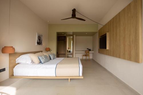 a bedroom with a large bed with a ceiling fan at Kouros Exclusive Hotel & Suites - Adults Only in Faliraki