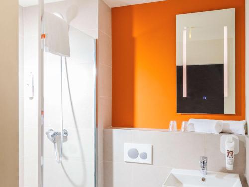 y baño de color naranja con ducha y lavamanos. en ibis budget Huerta De Murcia, en Murcia