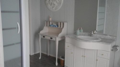 a white bathroom with a sink and a mirror at La Maison d'Hocquincourt in Bléneau