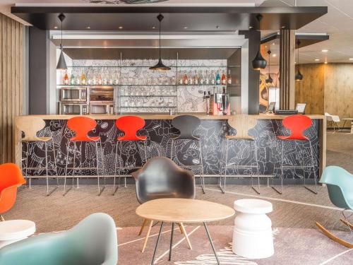 - un bar avec des tables et des chaises colorées dans une pièce dans l'établissement ibis Nantes Centre Tour Bretagne, à Nantes