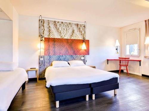 ムイユロン・ル・カティフにあるibis La Roche Sur Yon Vendespaceのベッド2台とテーブルが備わるホテルルームです。