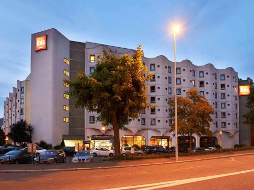 ein großes Gebäude mit Autos auf einem Parkplatz in der Unterkunft ibis Strasbourg Centre Historique in Straßburg