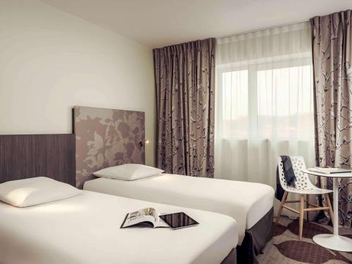 a hotel room with two beds and a table at Mercure Compiègne Sud in Compiègne