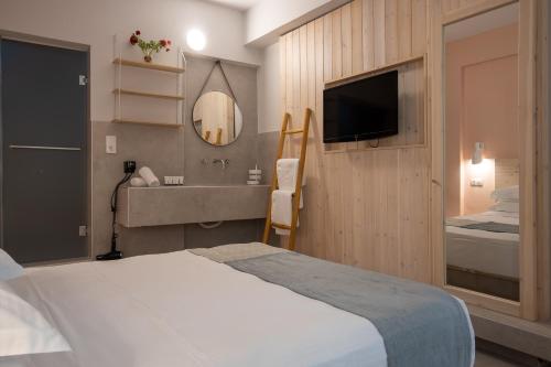 a bedroom with a bed and a sink and a mirror at Kouros Exclusive Hotel & Suites - Adults Only in Faliraki