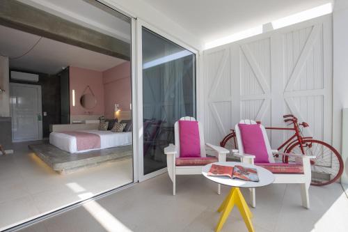 a bedroom with pink chairs and a bed and a bike at Kouros Exclusive Hotel & Suites - Adults Only in Faliraki