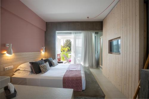 a bedroom with a large bed and a window at Kouros Exclusive Hotel & Suites - Adults Only in Faliraki