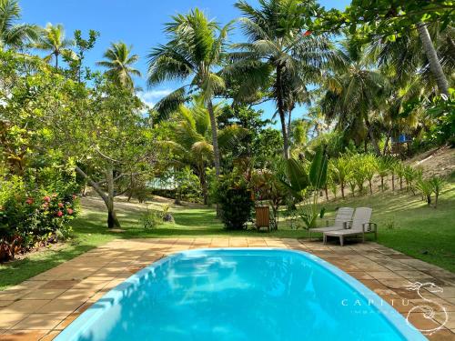 una piscina blu in un cortile con palme di Pousada Capitù a Imbassai