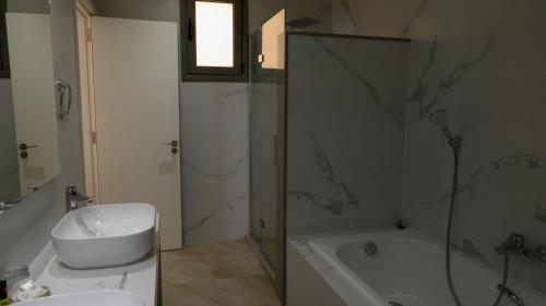 een badkamer met een douche, een bad en een wastafel bij Aphrodite Beach Hotel in Polis Chrysochous