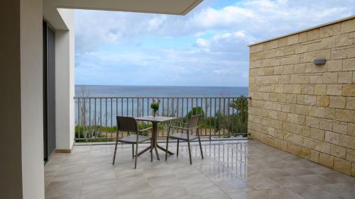 a table with chairs and a patio with a view of the ocean at Aphrodite Beach Hotel in Polis Chrysochous