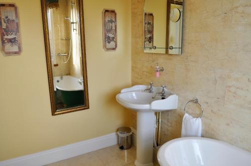 a bathroom with a sink and a mirror and a tub at Highfield House Guesthouse in Trim