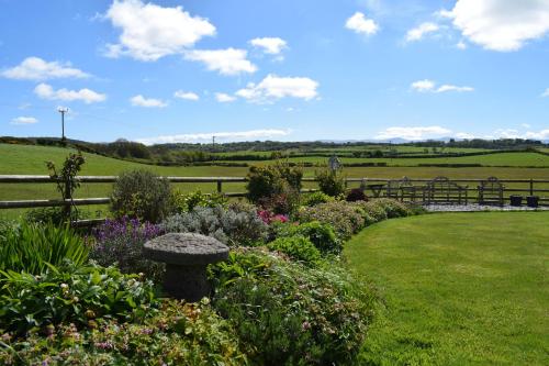 un jardín con flores y un banco y una valla en Parc Yr Odyn, en Pentraeth