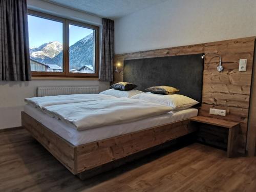 a bedroom with a large bed and a large window at Appartement Bergfuier in Holzgau