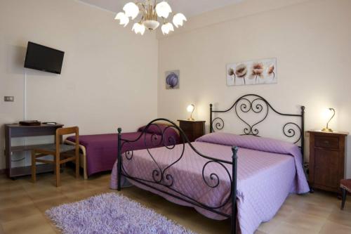 a bedroom with a purple bed and a tv at Armonia B&B in Trapani