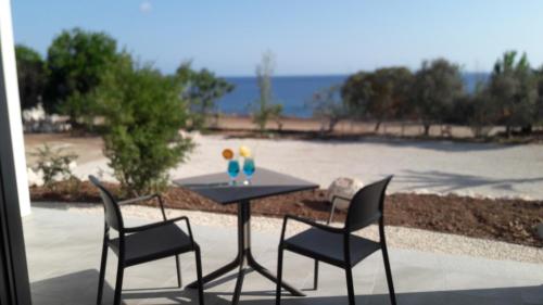 a table with three chairs and a table with a drink at Aphrodite Beach Hotel in Polis Chrysochous