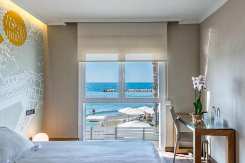 a bedroom with a window with a view of the ocean at Hotel La Chancla in Málaga