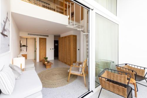 a living room with a white couch and a balcony at Kouros Exclusive Hotel & Suites - Adults Only in Faliraki
