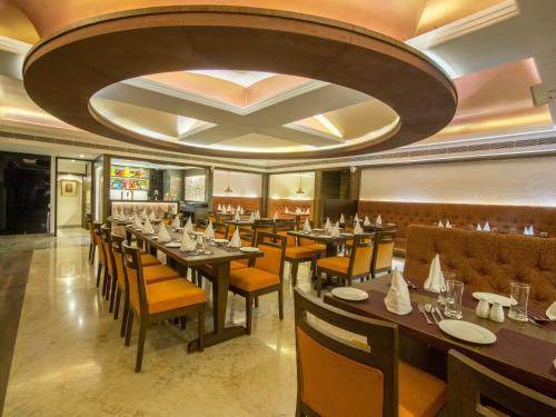 un ristorante con tavoli e sedie in legno e un soffitto di The Sonnet Jamshedpur a Jamshedpur