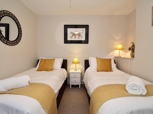 2 Einzelbetten in einem kleinen Zimmer mit Spiegel in der Unterkunft A Character Cottage in Historical Canterbury in Canterbury