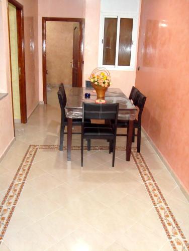 a dining room with a table and chairs on a tile floor at Yasmine Appartements in Temara