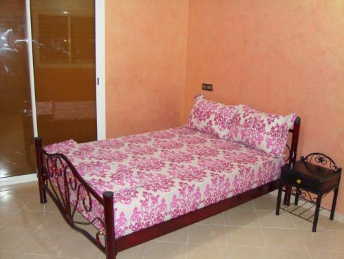 Bett in einem Zimmer mit rosa Bettwäsche und Kissen in der Unterkunft Yasmine Appartements in Temara